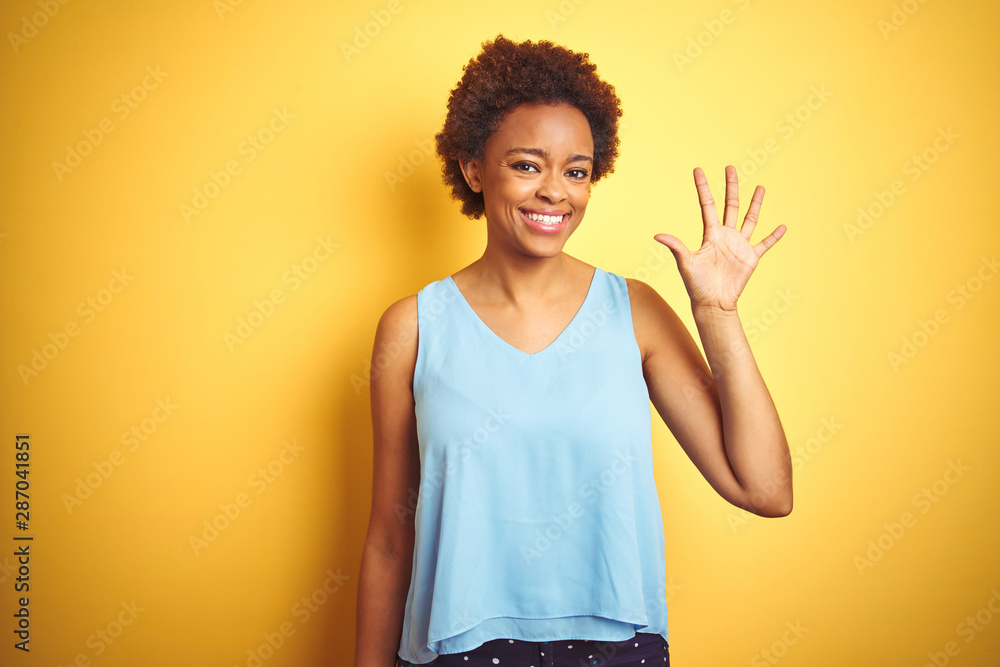 Beautiful african american woman wearing elegant shirt over isolated yellow background showing and pointing up with fingers number five while smiling confident and happy. Beautiful african american woman wearing elegant shirt over isolated yellow background showing and pointing up with fingers number five while smiling confident and happy.