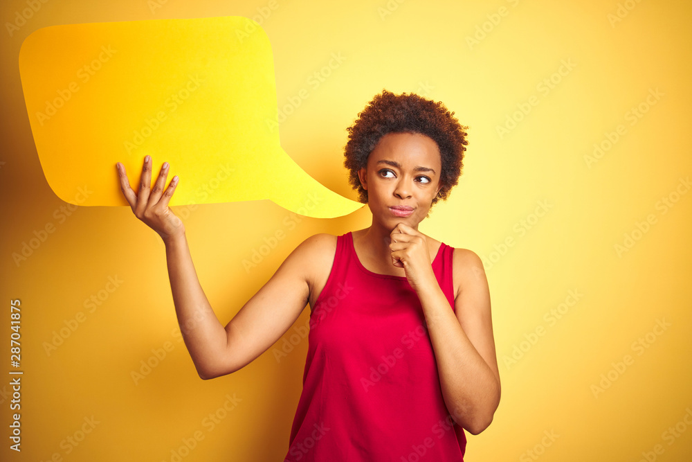 Young african american woman holding speech bubble over yellow isolated background serious face thinking about question, very confused idea Young african american woman holding speech bubble over yellow isolated background serious face thinking about question, very confused idea