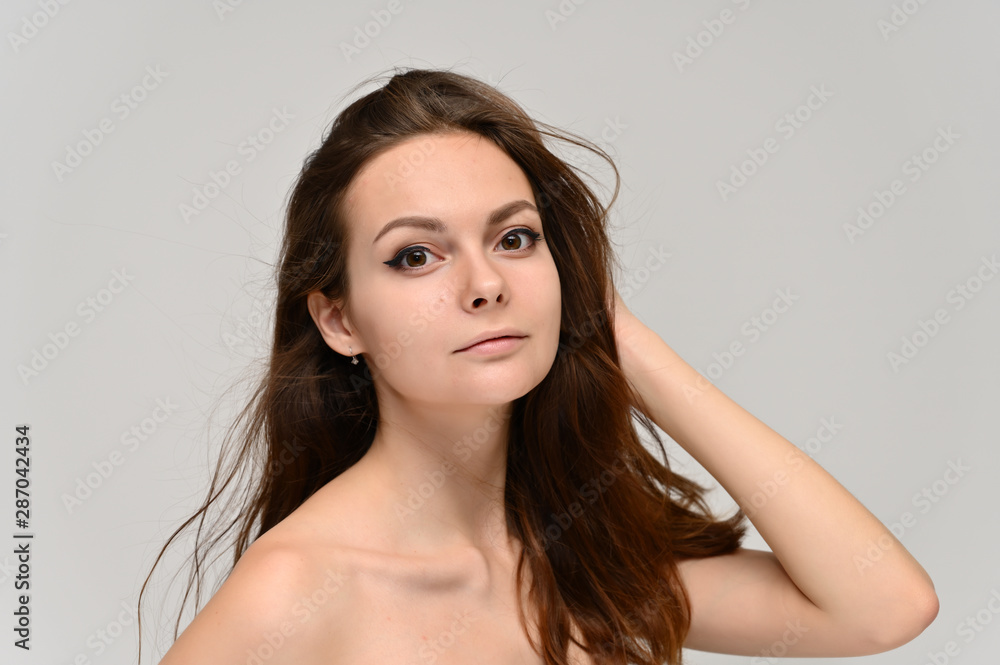 Fototapeta premium Close-up Portrait of a cute brunette girl, a young woman with beautiful curly hair and beautiful face skin. Beauty, brightness, smile, health.