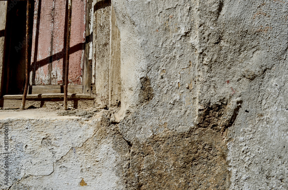 Old shelled wall with old window with rusty iron fence