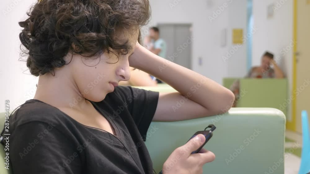 teenager boy sitting in the lobby of a children's clinic, waiting for a meeting with a doctor , using a smartphone. The concept of medical examination, health monitoring, preventive examination of teenager boy sitting in the lobby of a children's clinic, waiting for a meeting with a doctor , using a smartphone. The concept of medical examination, health monitoring, preventive examination of