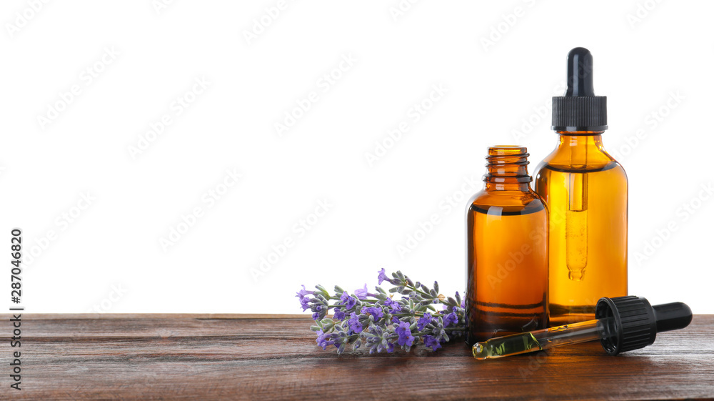 Bottles of essential oil and lavender flowers on wooden table against white background Bottles of essential oil and lavender flowers on wooden table against white background