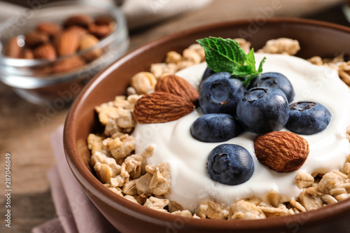 Bowl of tasty oatmeal with blueberries and yogurt on table, closeup