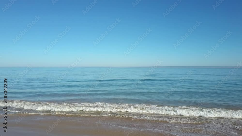 Aerial view of drone flight above calm and tranquil ocean water, with summer sunny blue sky and horizon as background and copy space. Aerial view of drone flight above calm and tranquil ocean water, with summer sunny blue sky and horizon as background and copy space.