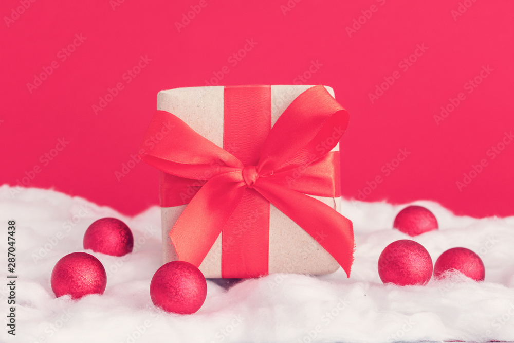 Christmas toys and gift with red ribbon, white snow made of cotton, red background, copy space. Winter holidays concept Christmas toys and gift with red ribbon, white snow made of cotton, red background, copy space. Winter holidays concept