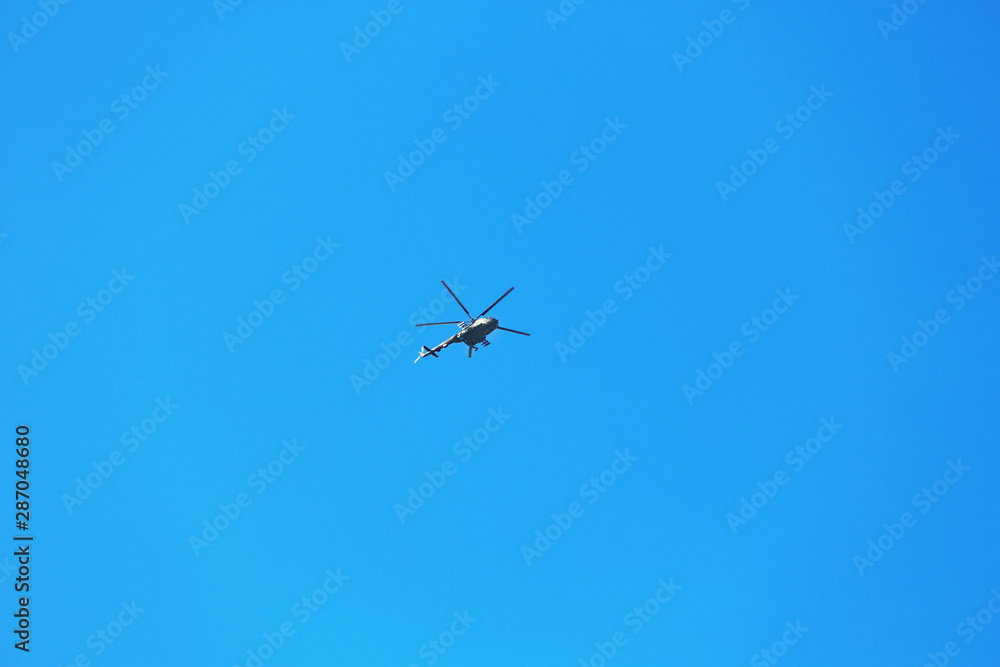 Modern military helicopter flying in blue sky Modern military helicopter flying in blue sky