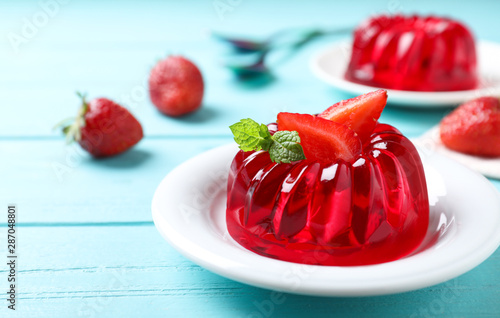 Foto Delicious red jelly with strawberry and mint on light blue wooden table