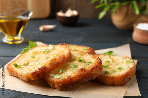 Slices of delicious toasted bread with garlic and herbs on blue wooden table  closeup