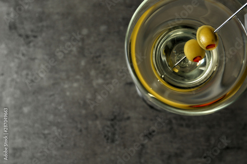Glass of Classic Dry Martini with olives on grey table, top view. Space for text