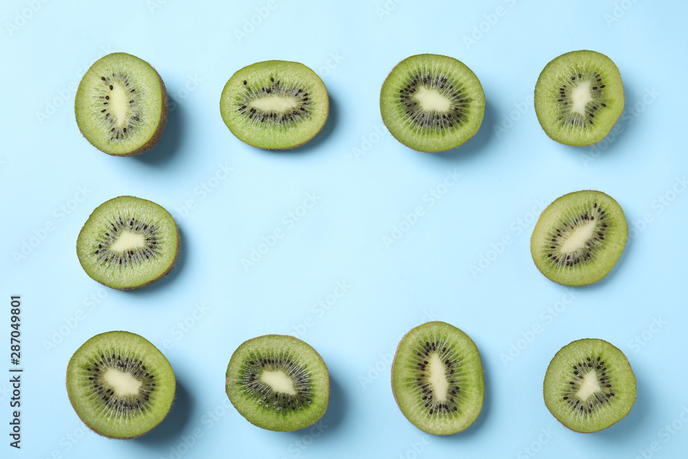 Fototapeta premium Frame made of fresh kiwis on light blue background, top view. Space for text