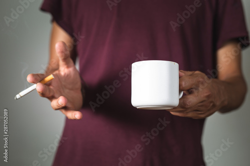 a person holding a coffee cup and a cigarette