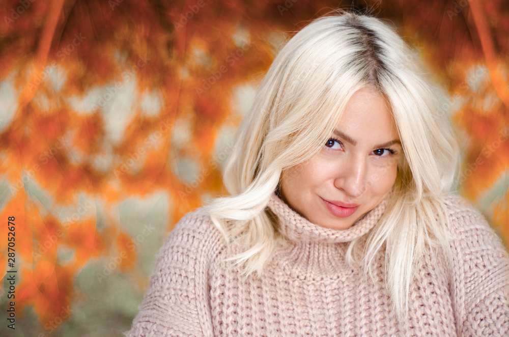 Blonde young woman closeup shot in the park with pink cozy sweater 