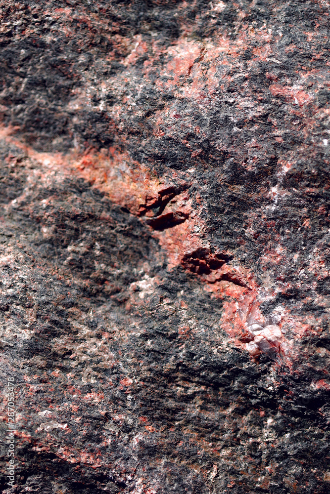 Fototapeta premium Abstract blurred natural background. Black with pink-orange rough surface of granite. Design and construction concept.