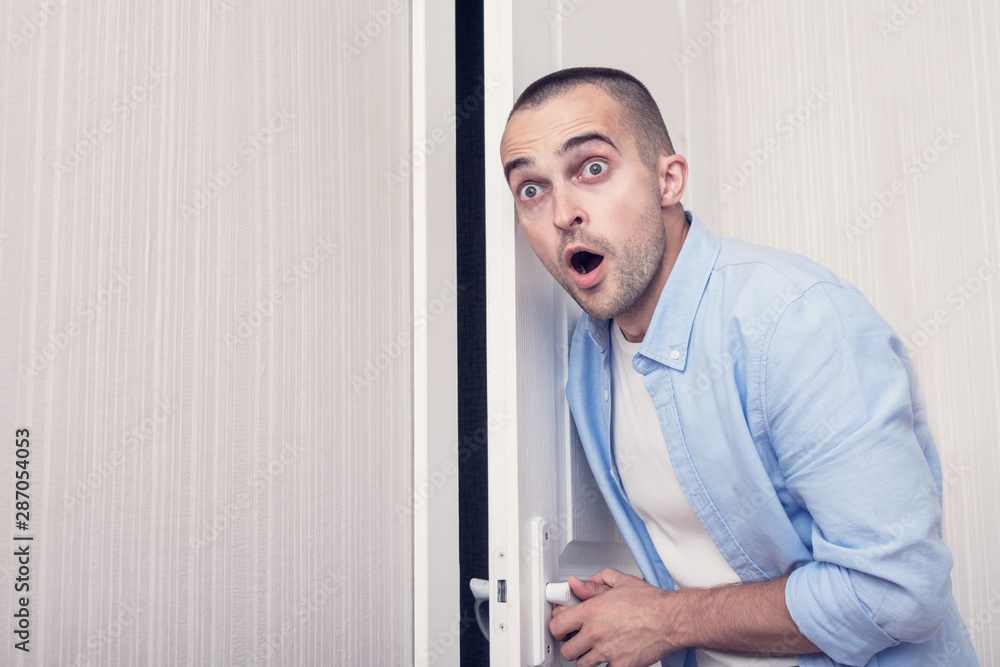 Fototapeta premium Shocked, stunned guy eavesdropper at the door, portrait, toned