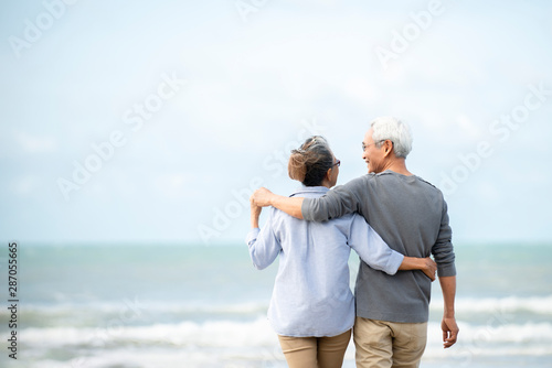 Happy asian senior couple  have fun and enjoy at the beach, senior man and woman hugging while walking on the beach Retirement Lifestyle Healthy  Travel Vacation Concept