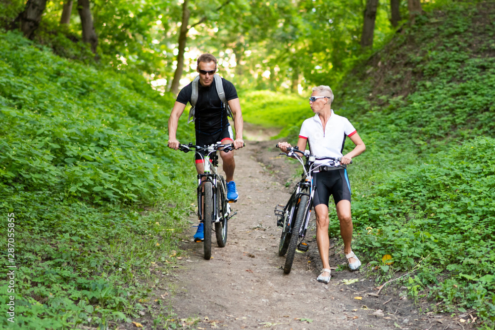 Fototapeta premium A man and a woman on bicycles go down the hill.
