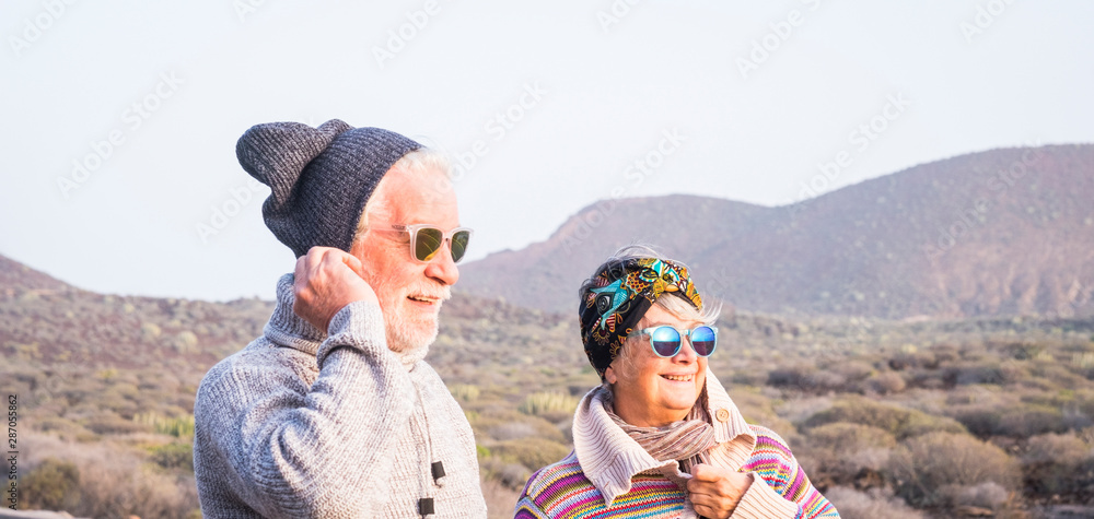 couple of seniors together looking at the horizon with the mountain in background - travelers at winter lifestyle concept - married mature people having fun together in outdoor leisure activity