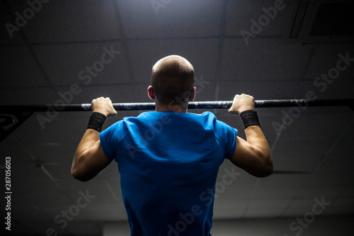 A man pulls himself up on a horizontal bar. Doing sports. Strong hands of a man. The strength and energy of the athlete on the crossbar.