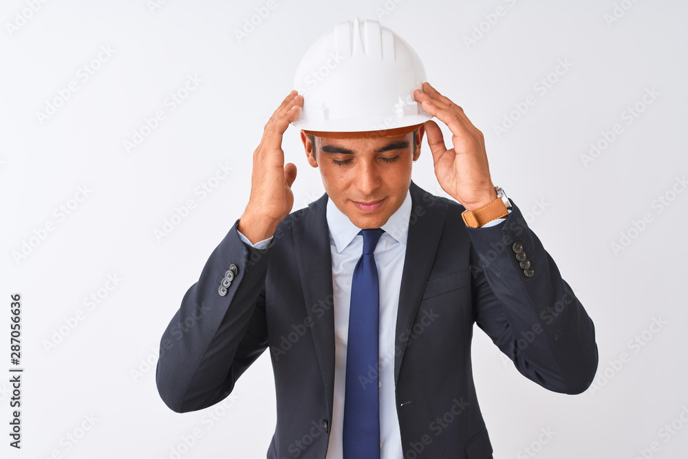 Young handsome architect man wearing suit and helmet over isolated white background with hand on head for pain in head because stress. Suffering migraine. Young handsome architect man wearing suit and helmet over isolated white background with hand on head for pain in head because stress. Suffering migraine.