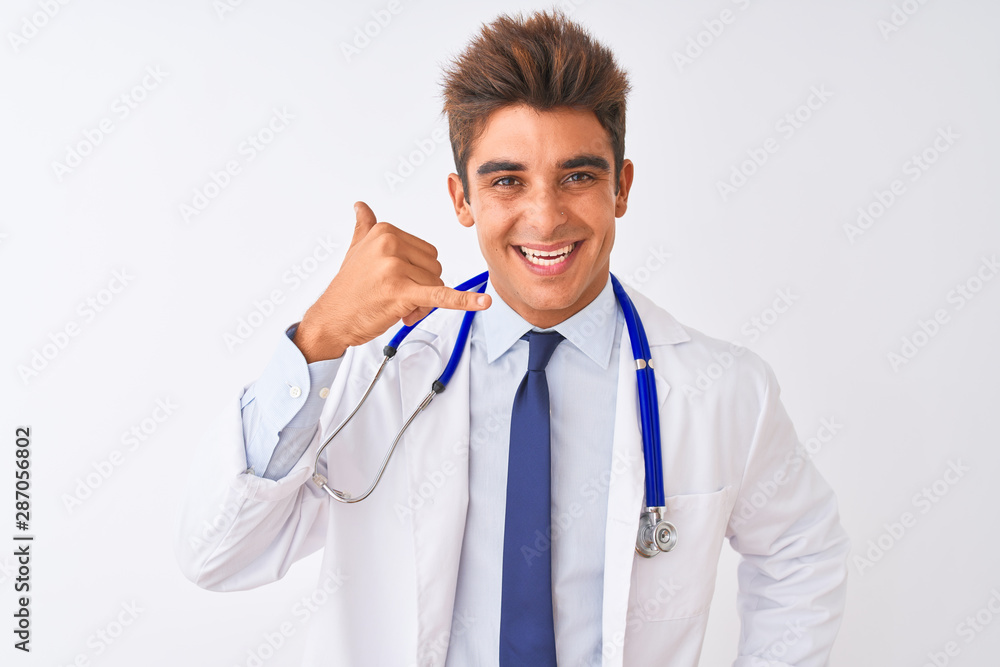 Young handsome doctor man wearing stethoscope over isolated white background smiling doing phone gesture with hand and fingers like talking on the telephone. Communicating concepts. Young handsome doctor man wearing stethoscope over isolated white background smiling doing phone gesture with hand and fingers like talking on the telephone. Communicating concepts.
