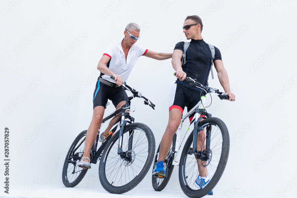 Man and woman with bicycles, a woman holds a man by the shoulder, on a light background. Man and woman with bicycles, a woman holds a man by the shoulder, on a light background.
