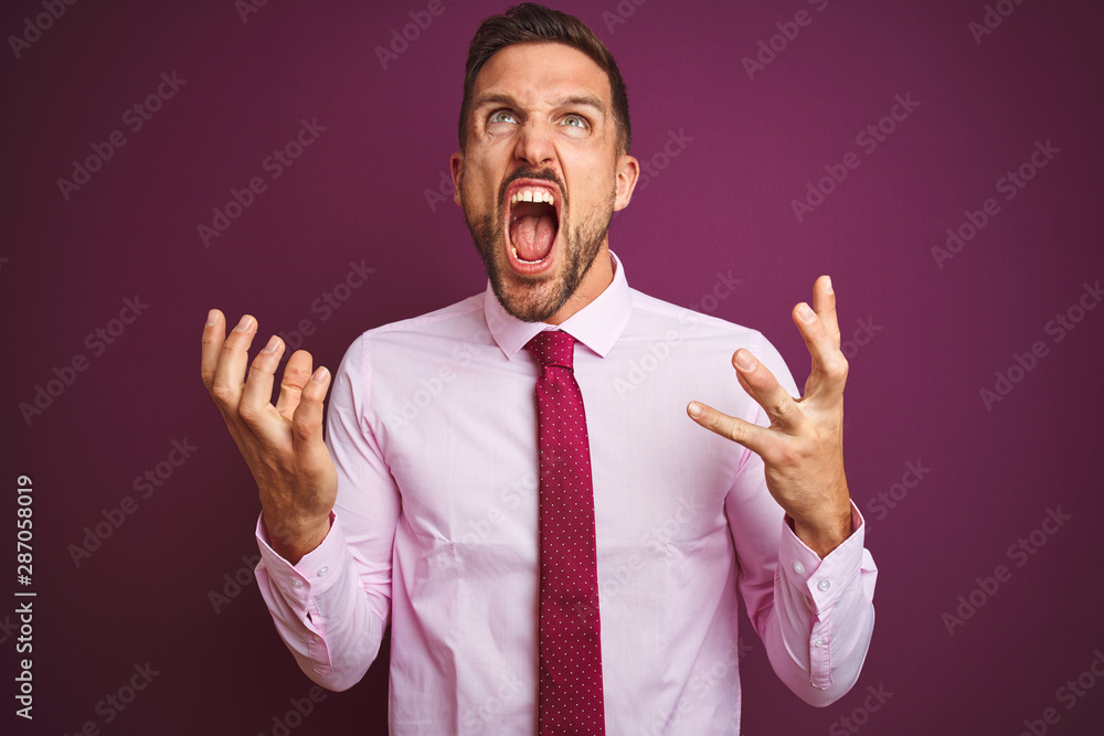 Young business man wearing elegant shirt and tie over purple isolated background crazy and mad shouting and yelling with aggressive expression and arms raised. Frustration concept. Young business man wearing elegant shirt and tie over purple isolated background crazy and mad shouting and yelling with aggressive expression and arms raised. Frustration concept.