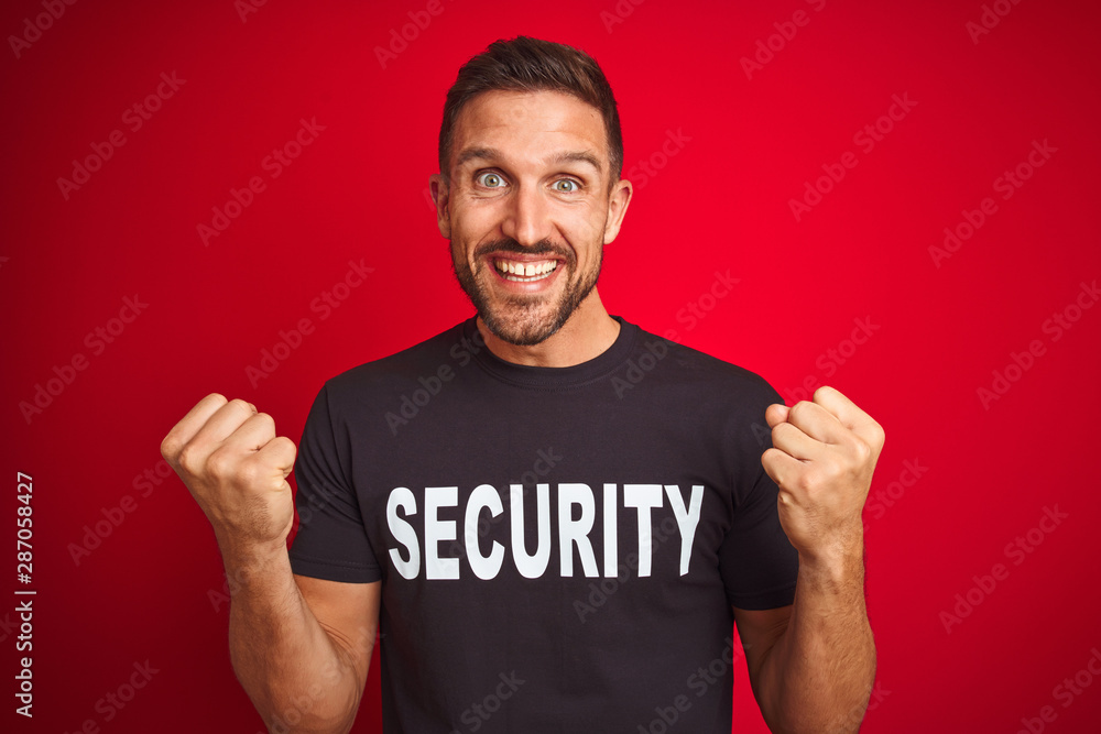 Young safeguard man wearing security uniform over red isolated background celebrating surprised and amazed for success with arms raised and open eyes. Winner concept. Young safeguard man wearing security uniform over red isolated background celebrating surprised and amazed for success with arms raised and open eyes. Winner concept.
