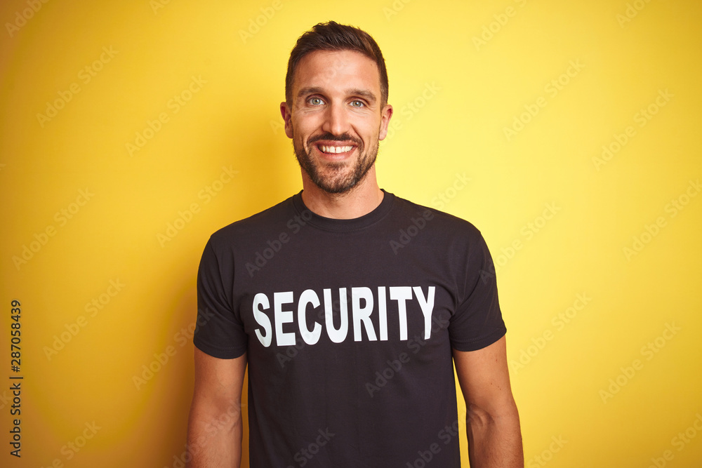 Young safeguard man wearing security uniform over yellow isolated background with a happy and cool smile on face. Lucky person. Young safeguard man wearing security uniform over yellow isolated background with a happy and cool smile on face. Lucky person.