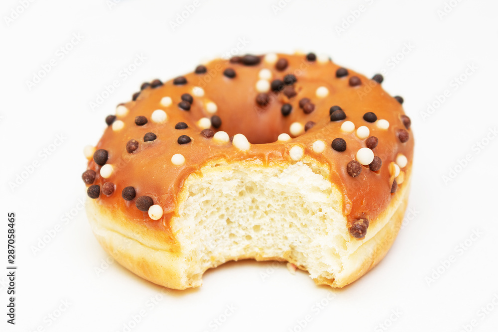 Bitten brown donut with bright sprinkles, white background, side view