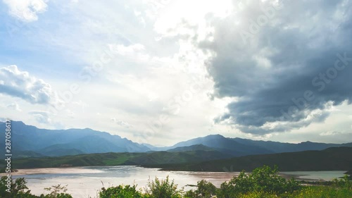 grey and white clouds float in boundless sky over calm lake surrounded by green grass against distant hills on horizon motion graph. 3D Concept travel majestic nature beauty world holidays recreation photo