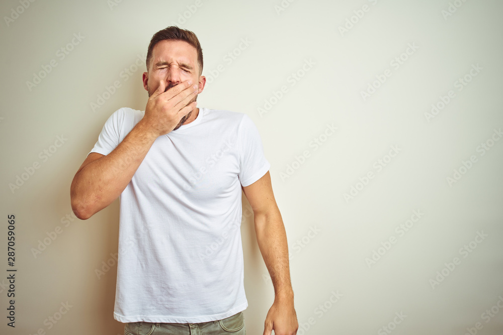 Young handsome man wearing casual white t-shirt over isolated background bored yawning tired covering mouth with hand. Restless and sleepiness. Young handsome man wearing casual white t-shirt over isolated background bored yawning tired covering mouth with hand. Restless and sleepiness.
