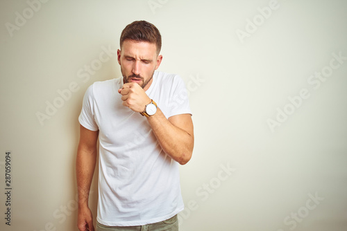 Young handsome man wearing casual white t-shirt over isolated background feeling unwell and coughing as symptom for cold or bronchitis. Healthcare concept.