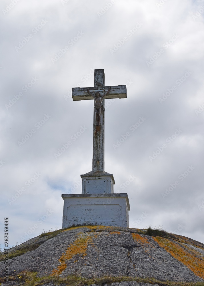 front view of a large crucifix on top of a hill, clouds in the background  