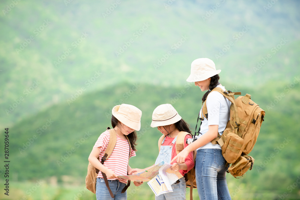 Happy tourist asian girl with two little looking on map with mountain background at natural park, travel education environment lifestyle concept Happy tourist asian girl with two little looking on map with mountain background at natural park, travel education environment lifestyle concept
