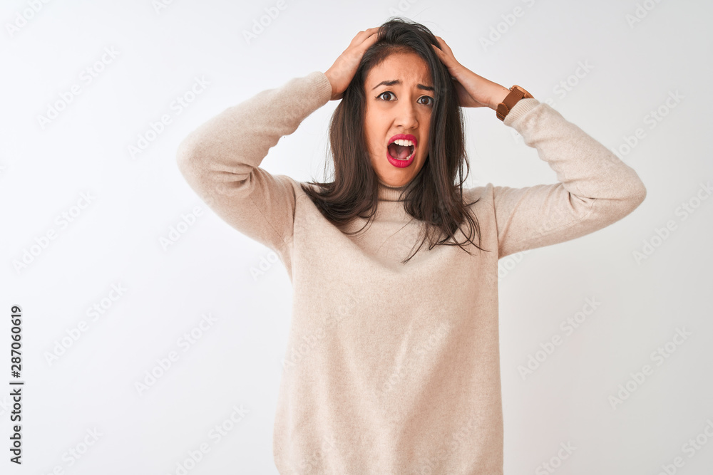 Beautiful chinese woman wearing turtleneck sweater standing over isolated white background Crazy and scared with hands on head, afraid and surprised of shock with open mouth Beautiful chinese woman wearing turtleneck sweater standing over isolated white background Crazy and scared with hands on head, afraid and surprised of shock with open mouth
