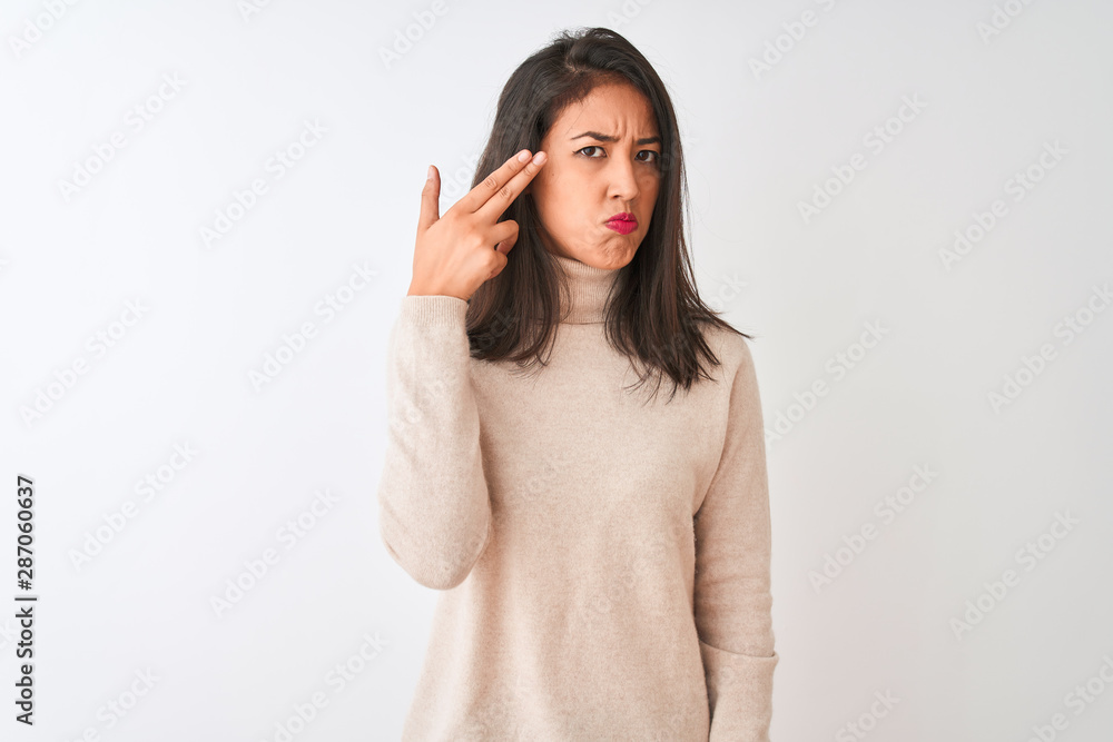 Beautiful chinese woman wearing turtleneck sweater standing over isolated white background Shooting and killing oneself pointing hand and fingers to head like gun, suicide gesture. Beautiful chinese woman wearing turtleneck sweater standing over isolated white background Shooting and killing oneself pointing hand and fingers to head like gun, suicide gesture.