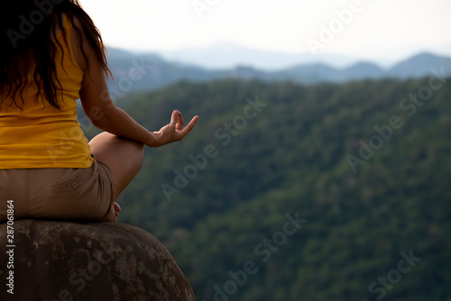 Close up on woman sitting on the rock in natural park doing yoga outdoors , Healthy lifestyle relaxation wellness Concept