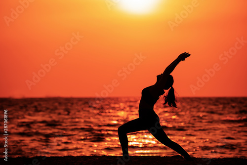 Silhouette of woman doing yoga outdoors  female practicing yoga fitness exercise on the beach at sunset   Healthy ifestyle relaxation wellness  Concept