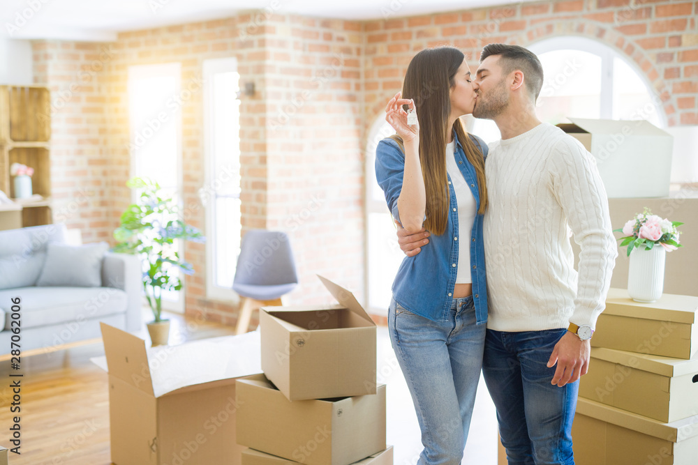 Young couple moving to a new home, hugging in love showing keys of new apartment smiling very happy Young couple moving to a new home, hugging in love showing keys of new apartment smiling very happy