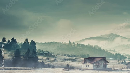 Rural village highland landscape with building surrounded by evergreen trees and snow against high hills, zoom in. Nature landscape, habitat, travel. Slow motion, parallax, time lapse 4K. Cinematic photo