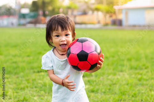Happy Asian baby child girl playing ball toys at the field playground. She smiling and wearing a yellow shirt. Baby aged of 1-2 years old.
