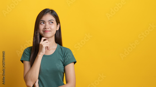 Photo beauty asian teenager in green tee shirt thinking / imagination / question isolated on yellow background in studio
