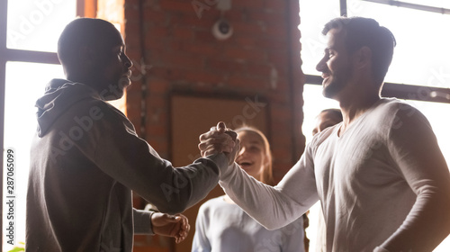 Happy diverse male buddies greeting at group meeting photo