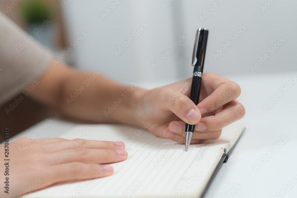 Close up hands of person writing note to notebook pages. Close up hands of person writing note to notebook pages.