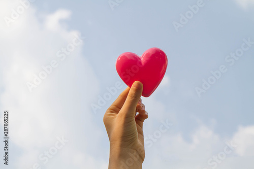 Hand holding heart with blue sky