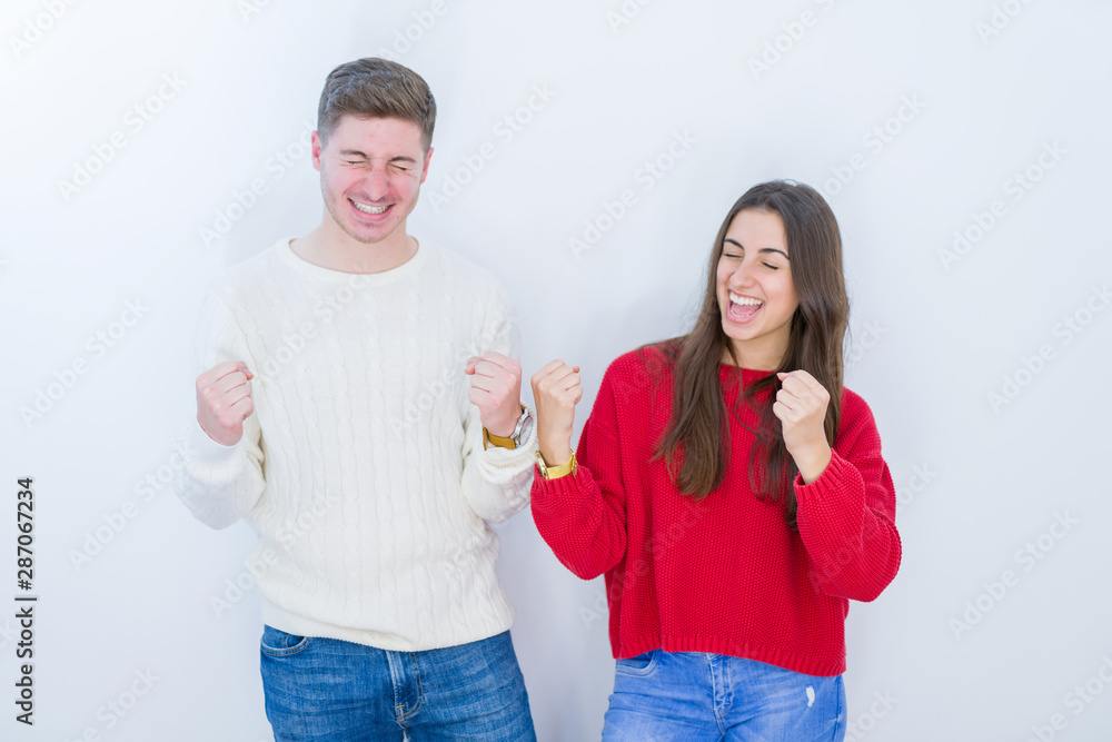 Beautiful young couple over white isolated background very happy and excited doing winner gesture with arms raised, smiling and screaming for success. Celebration concept.