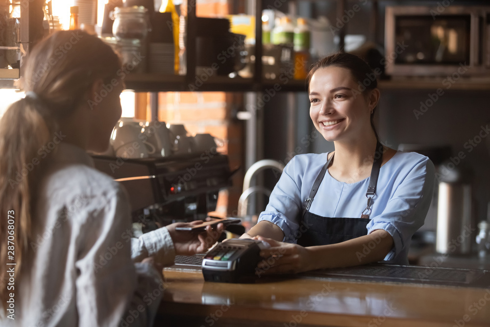 Female customer pay with phone on nfc with smiling barista