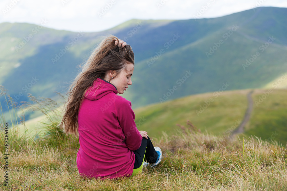 Young girl straightening hair in the mountains with a beautiful landscape. Rear view. Young girl straightening hair in the mountains with a beautiful landscape. Rear view.