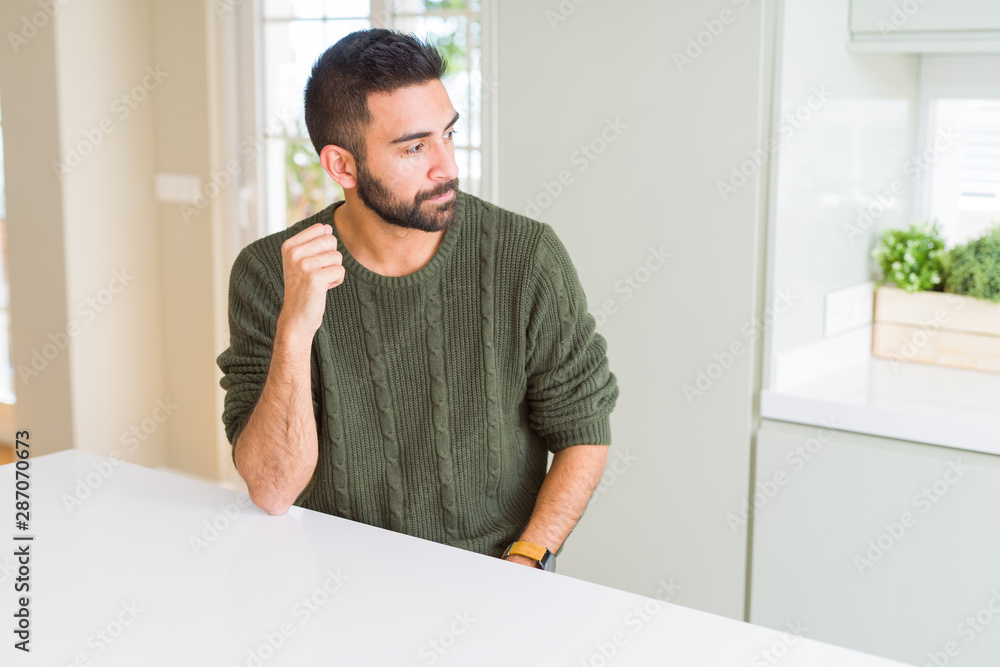 Handsome hispanic man wearing casual sweater at home looking to side, relax profile pose with natural face with confident smile.