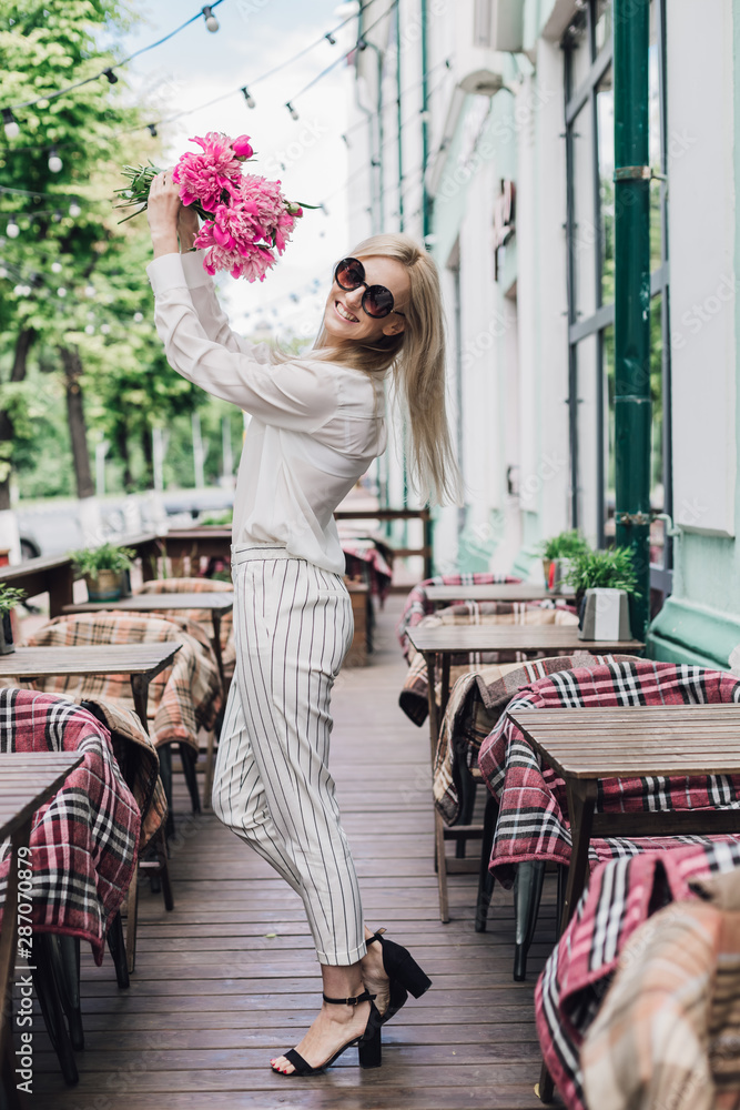 Stylish young woman with a bouquet of flowers in a summer cafe